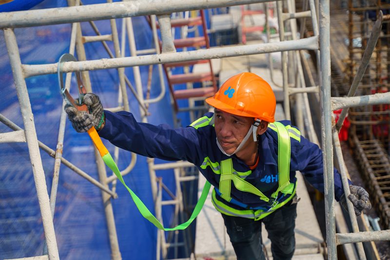 Thợ thi công thực hiện cách căng lưới bao che giàn giáo cao tầng an toàn