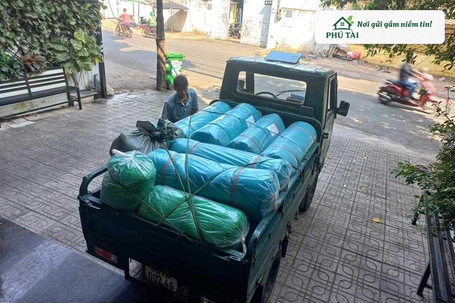 Xe tải chở đầy ắp các cuộn lưới bao che công trình màu xanh được chằng buộc an toàn giao tận công trình